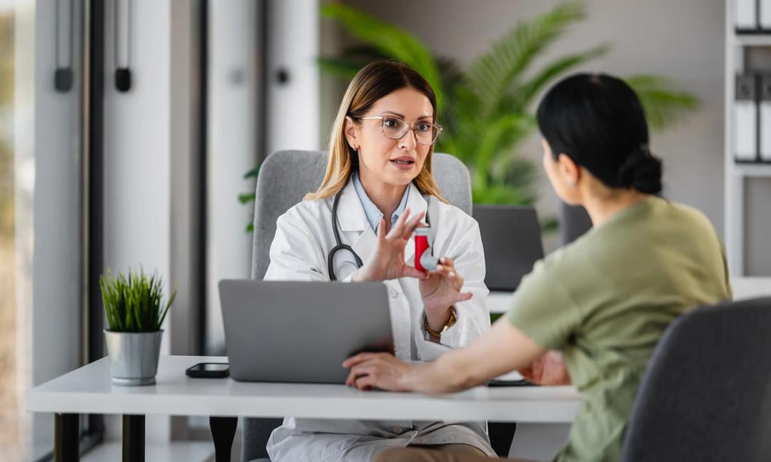 Female doctor consulting patient about inhaler use and treatment in medical office