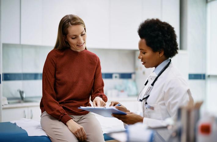 African American doctor and her female patient analyzing medical report after examination in the hospital. Focus is on female patient.