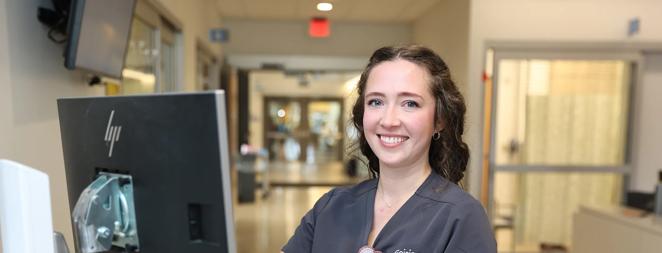 Kaitlyn Snyder Nurse posing at nursing station in hallway