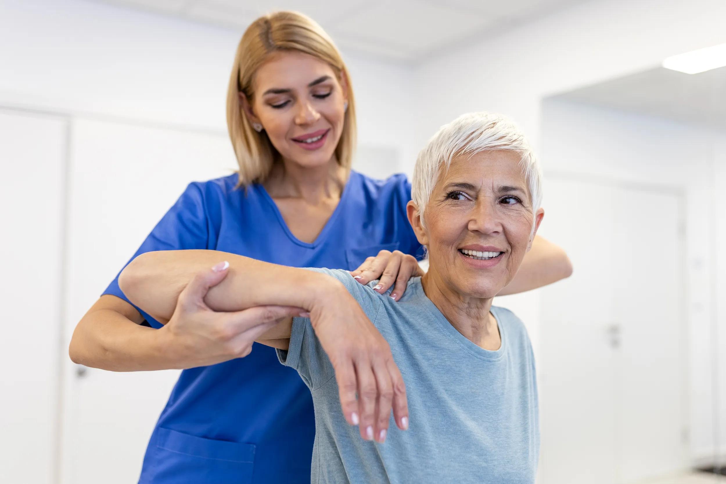 Doctor or Physiotherapist working examining treating injured arm of senior patient, stretching and exercise, Doing the Rehabilitation therapy pain in clinic.